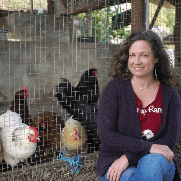 A woman sitting in front of chickens.