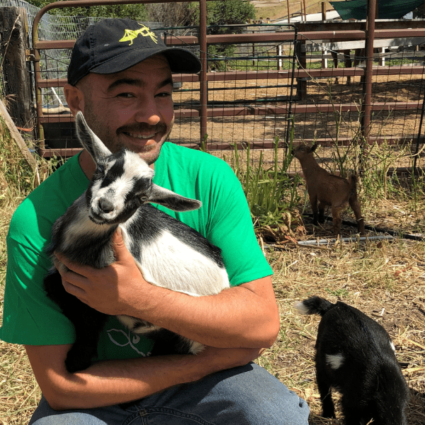 A man holding a baby goat in his hands.