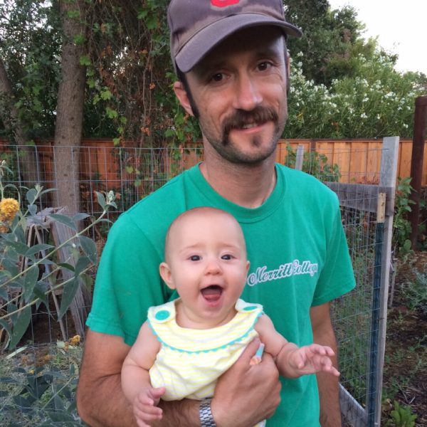 Father and baby smiling in garden.