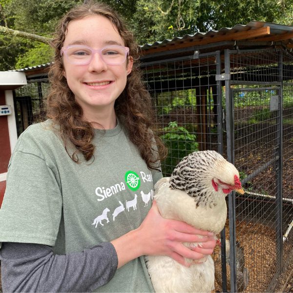Smiling girl holding a chicken in her arms.