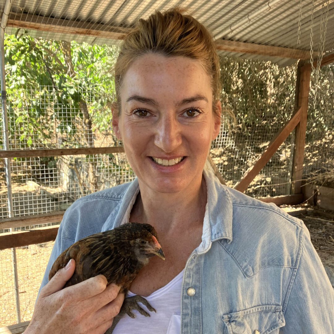 Woman smiling, holding a brown chick.